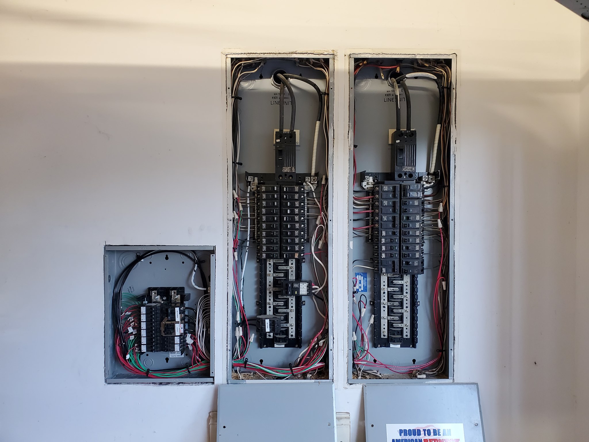 Three electrical circuit breaker panels with open covers reveal multiple wires and switches inside.